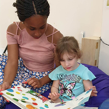 Une éducatrice stagiaire fait la lecture à une enfant de notre maison de répit à Montréal. 